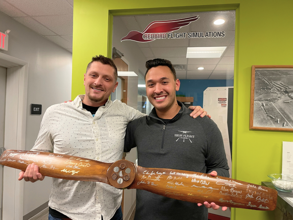 Two High Flight Academy students celebrating their Checkride by signing the commemorative propeller. 